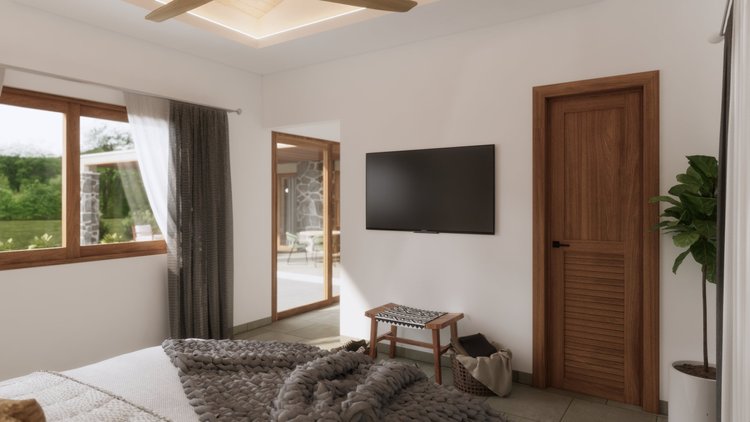 The image shows a bedroom with a window on the left, a wall-mounted TV in the center, and a wooden door on the right. There is a bed at the bottom with a chunky gray blanket, a small wooden bench, and a basket with a cloth near the door. Outside, thr