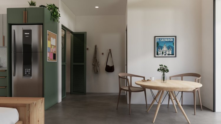 Modern dining area with a round wooden table, two wooden chairs, a small plant in a vase, and a picture of El Salvador on the wall. The space features minimalist decor with a white wall and wooden floors.