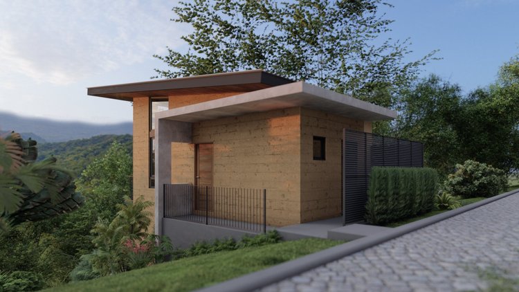 Modern house with flat roof, wooden exterior, and black metal fence, surrounded by greenery and hills in the background.