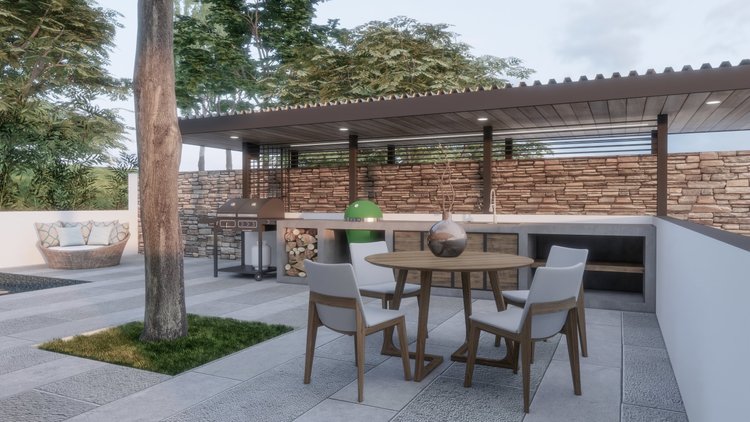 Modern outdoor patio with a round wooden table and four white cushioned chairs. A decorative vase with branches on the table, and a built-in grill and wood storage under a covered roof. There is a brick wall, trees, and greenery in the background.